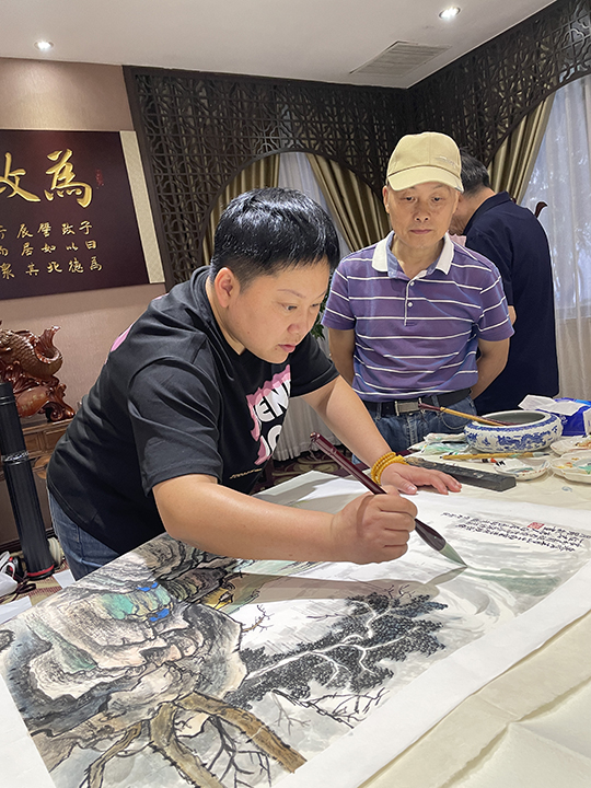 华夏国艺书画艺术中心副主任、中企报盟信息科学研究院副院长高健林在小型创作研讨会上欣赏学生华夏国艺书画艺术中心会员、特聘书画家罗敏创作.jpg